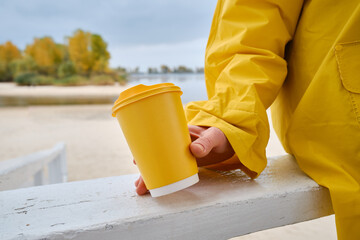 Yellow paper cup with coffee in woman hand. Time for drink coffee in city. Coffee to go. Enjoy...