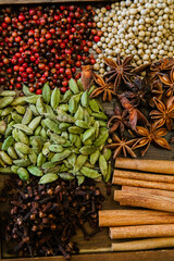 Cinnamon, clove, star anise, cardamom, juniper, nutmeg, ginger and pepper whole spices on a wooden tray