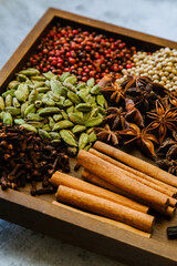 Cinnamon, clove, star anise, cardamom, juniper, nutmeg, ginger and pepper whole spices on a wooden tray