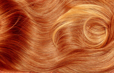 Red hair close-up as a background. Women's long orange hair. Beautifully styled wavy shiny curls....