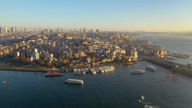 At sunset, the drone comes over the sea towards the Galata Tower and takes photos. Aerial view of sea and land traffic. Istanbul, Turkey. 