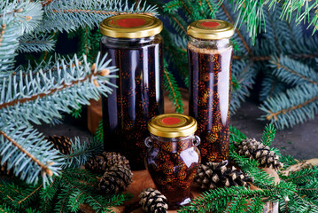 Jam from young pine cones in syrup on a background with pine branches