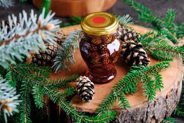 Jam from young pine cones in syrup on a background with pine branches