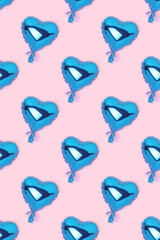 Repetitive pattern made of blue inflatable foil balloons in a heart shape. Creative composition on a pink background.
