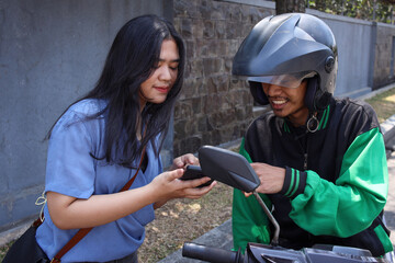 Happy young woman ordering a commercial motorcycle taxi driver by smartphone