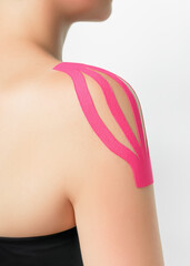 a woman wears pink kinesio tape on her shoulder. kinesio taping of the shoulder to relieve pain in the shoulder joint - obrazy, fototapety, plakaty