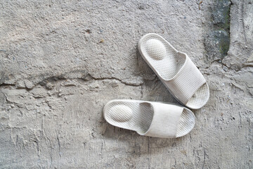 Old white sandals placed on cracked concrete surface. top view photo.