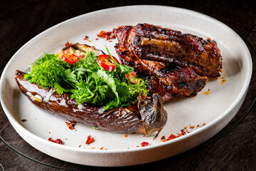 grilled pork ribs with baked eggplant on plate