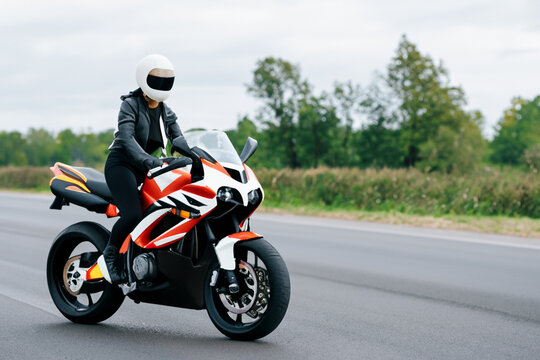 a girl in a leather jacket and a helmet rides a motorcycle. AI GENERATE