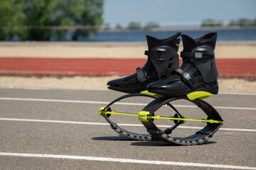 Black boots for jumping on a blurred background of nature. Kangoo jumping shoes for fitness with yellow accents.