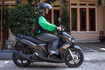 Full length photo of young Asian man works as a motorcycle taxi driver on the street