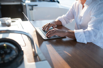 Confident man in sunglasses working on a laptop while sailing on a yacht