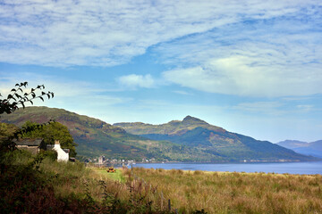 Fototapeta na wymiar From across Loch Goil, a distant view of Carrick Castle with hazy hills in the background