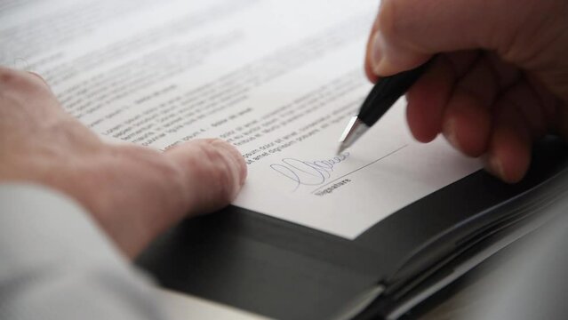 Hand signing a document, close up