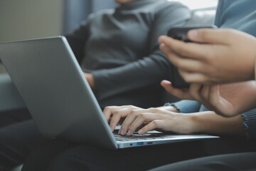 Naklejka premium Three beautiful Asian girls using smartphone and laptop, chatting on sofa together at cafe with copy space, modern lifestyle with gadget technology or working woman on casual business concept