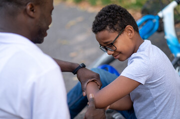 Dad helping his son after falling donw from the bike