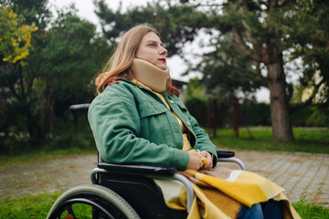 30s woman with a neck brace sitting on wheelchair outdoors