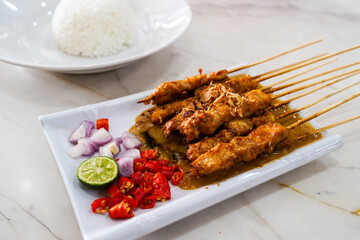 Grilled chicken satay with peanut sauce. served with sliced red chilies, red onions and lemon,