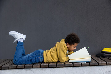 Obraz premium Schoolboy in yellow hoodie looking involved while doing homework
