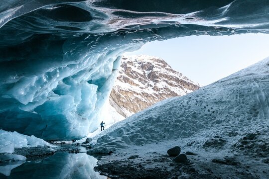 Silhouette of a hiker at the entrance of an ice cave