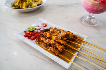 Grilled chicken satay with peanut sauce. served with sliced red chilies, red onions and lemon,