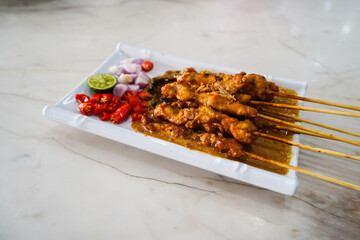 Grilled chicken satay with peanut sauce. served with sliced red chilies, red onions and lemon,