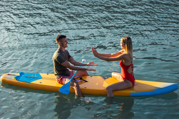 Young woman and sitting on sup board in the open ocean.