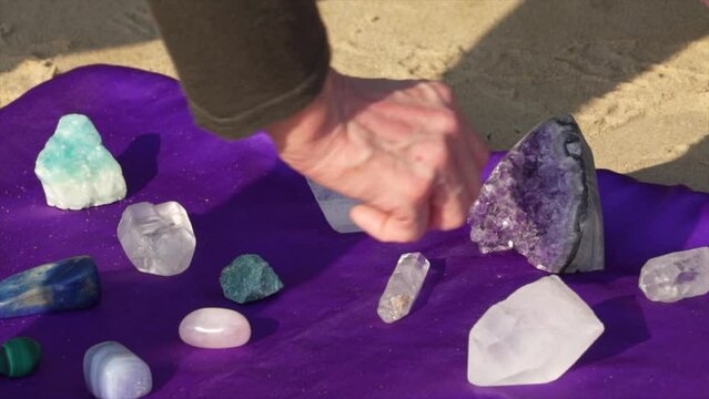 Closeup shot of a female healer hand arranging the healing crystals on a purple cloth outdoors