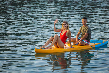 Woman and man surfing in ocean sea on surfboard, couple doing water sport.
