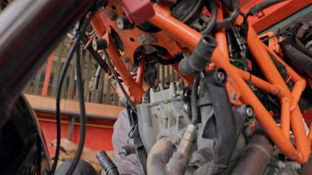 A 50 Year Old Asian Woman's Workshop: Restoring the Engine of an Orange Motorcycle