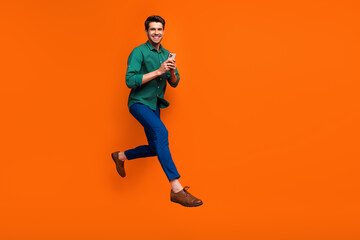 Full body cadre of young funky businessman running with smartphone enjoy shopping no commission estore isolated on orange color background