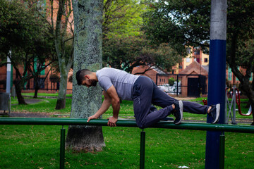 Fototapeta premium young sportsman in sportswear doing front squat on one leg forward with hands folded outside in city park during routine workout in morning