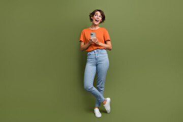 Full length photo of impressed ecstatic girl in eyewear hold smartphone look at proposition empty...