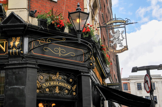 Decorative sign above the entrance and a hanging sign with a Lion of a traditional English pub in London, UK.