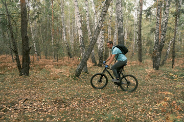  active lifestyle.A cyclist with a backpack rides a black mountain bike through a coniferous forest in autumn.Mountain Bike