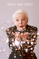 short hair stylish senior woman in tuxedo with glass with champagne blowing confetti celebrating new year. Fun, lifestyle, style, age concept