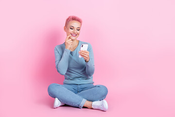 Obraz na płótnie Canvas Full size photo of pretty girl dressed blue sweatshirt pants hold smartphone instagram whatsapp twitter isolated on pink color background
