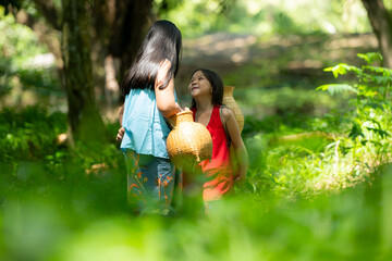 Fototapeta premium Two girls Asian women with traditional clothing stand in the rainforest. They had fun playing together before assisting Grandpa in catching fish in a nearby lake.