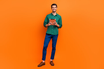 Full length body photo of optimistic business secretary ceo monitor his information company tablet isolated over orange color background