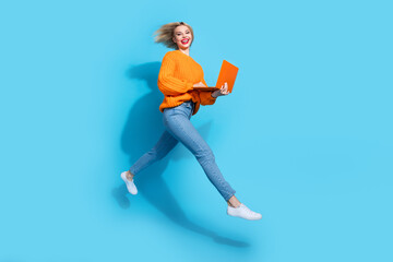 Full length profile photo of energetic cheerful person jump rush use netbook isolated on blue color background