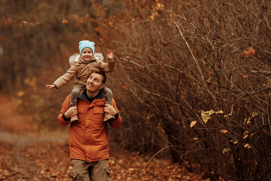 Happy family father and daughter on a walk in the autumn leaf fall in the park. Concept of fatherhood, adventure and family with one child.