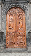 Detail of the main wooden door with engravings of saints and angels of the church of El Jordan