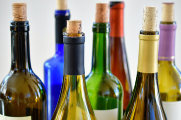 A collection of colorful open wine bottles with corks in them grouped together at a party.