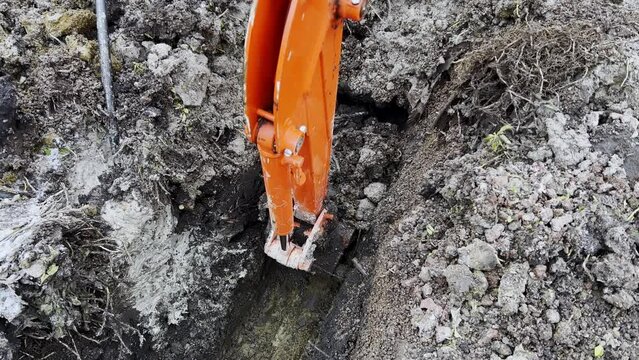 A bucket of the excavator getting soil from the ground during the winter time. Close up footage