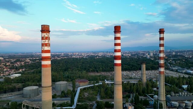 Aerial drone footage of a thermal power plant producing electricity during sunset. 4k high angle fly over shot of an industrial natural gas power station.

