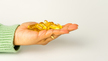 Holding Omega-3-rich wild salmon and fish oil capsules against a gentle off-white background.