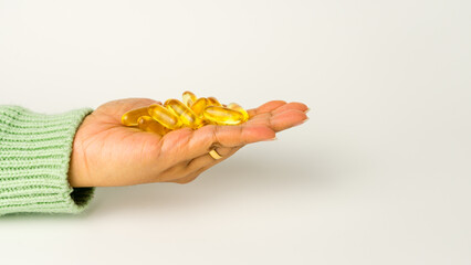 Obraz premium Holding Omega-3-rich wild salmon and fish oil capsules against a gentle off-white background.
