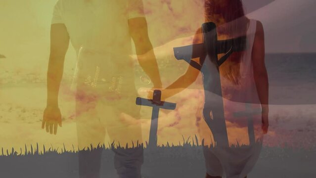 Animation of jesus crucifix statue, cloudy sky, caucasian couple holding hands and walking on beach