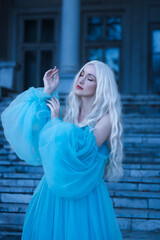 Fototapeta premium Beautiful woman with a elegant curly hairstyle. Princess. A luxurious blue dress with a long train