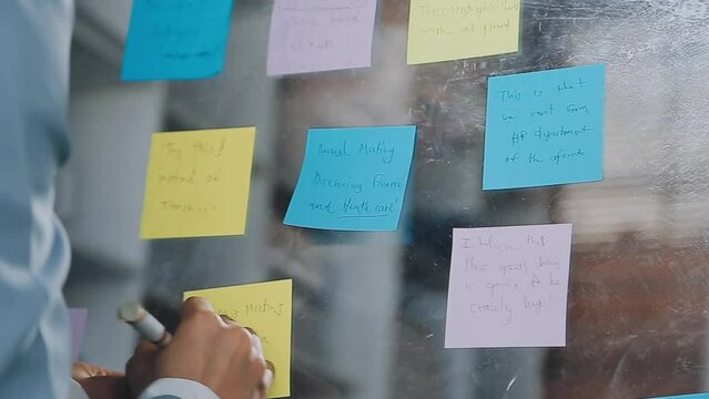 Young asian business woman working on project plan using sticky papers notes on glass wall, people meeting to share idea, Business design planning concepts.